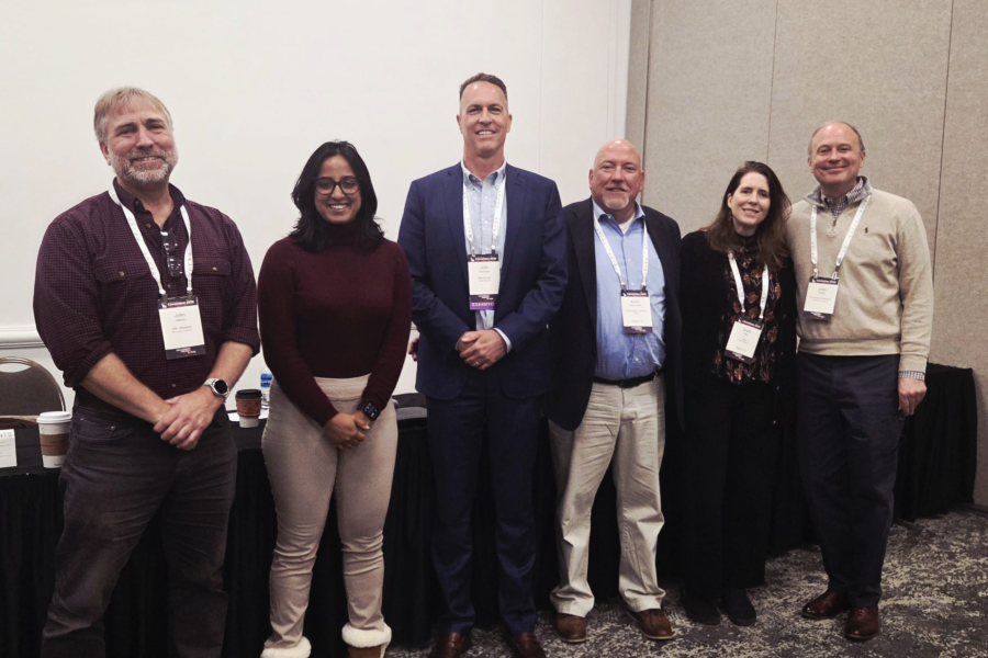 Five members of the AI panel pose in front of a table