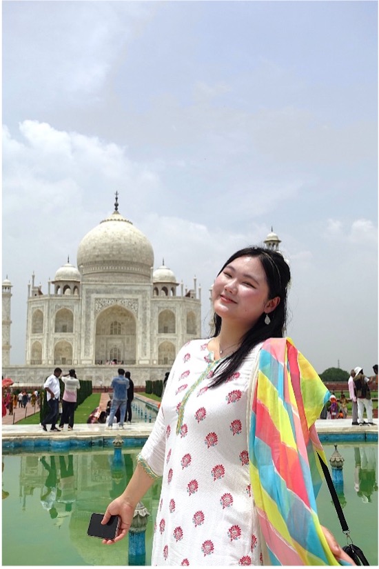 Sarang posing in front of a large building outside and smiling