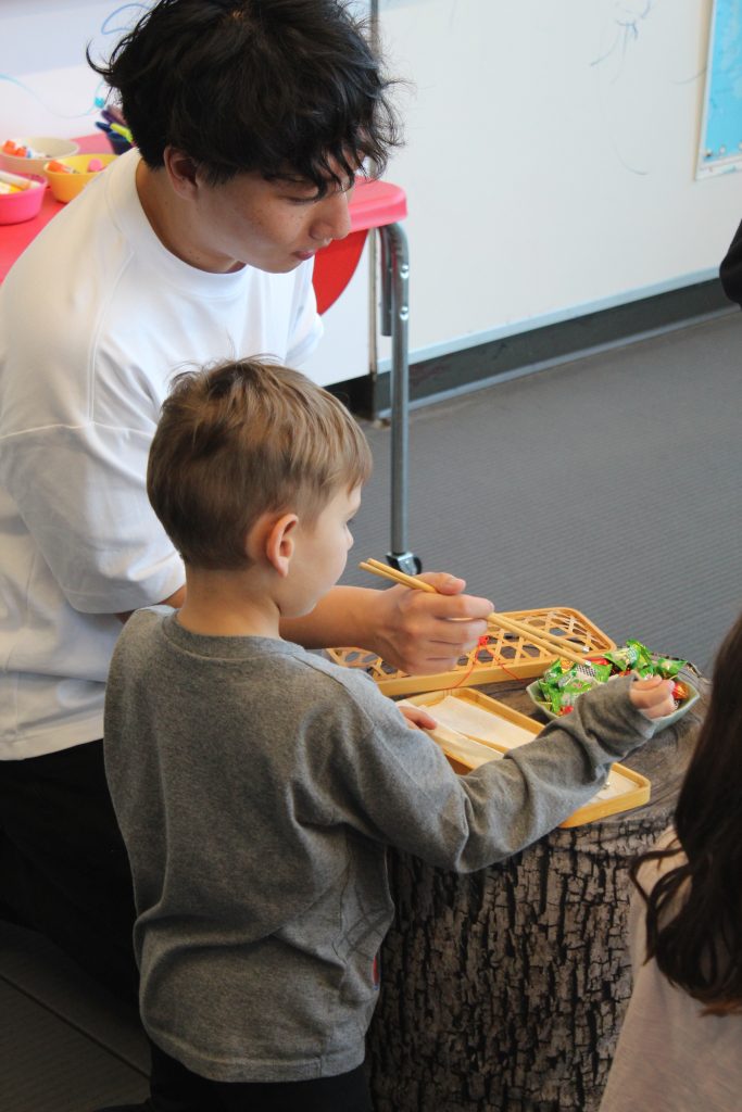 Tony Jing helps a student practice their chopstick skills