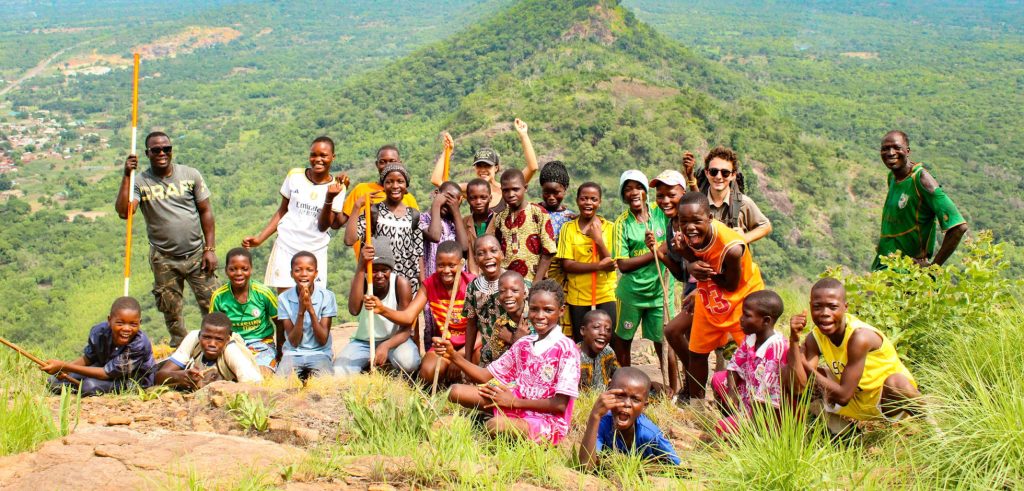 A Peace Corps volunteer stands with a group on a mountainside